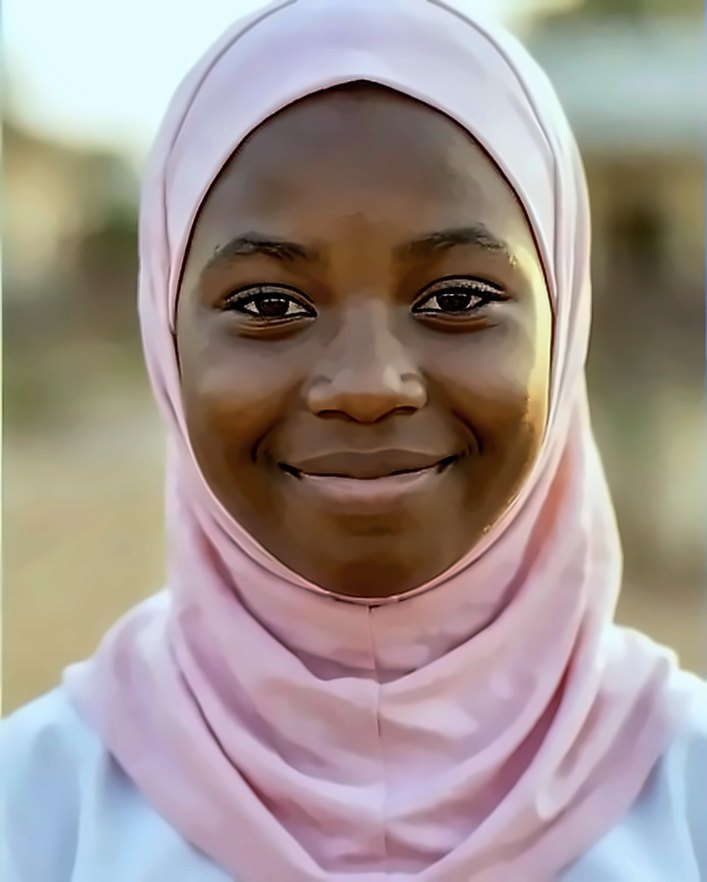 A smiling girl in a pink headscarf
